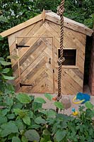 Child's playhouse made from raw recycled materials in 'Inspiration in the Raw' garden at BBC Gardener's World Live 2018.