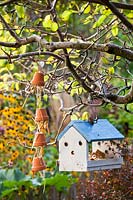 Upturned pots filled with straw as a bug house and a bird house hanging from pear tree.