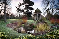 Temple of the Four Winds at Doddington Hall, Lincolnshire on a March morning set beside a small pond fringed with the colourful stems of cornus and willows