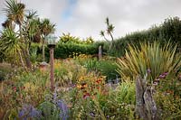 The Beth Chatto Garden with glass domed bird table, grasses, Echinacea, Rudbeckia, Perovskia, Phormium, Cordyline and Crocosmia