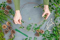 Woman adding Ivy to a thin metal wire wreath