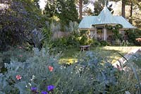 Pool house at Chanticleer Garden with blue metal roof. Border plantings in shades of silvery-blue accented with coral and black