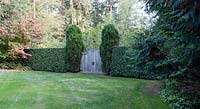 Double cedar gates allow a tractor to enter the vegetable garden, but the dense, sheared 8-9-foot hedge of Prunus lusitanica keeps the deer out.