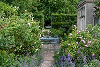 Small paved courtyard planted with old fashioned scented roses such as Rosa 'Jacques Cartier' and 'Fantin Latour'.