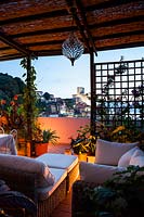 Lit outdoor living area under pergola on terrace with view Lerici's castle and harbour at night