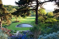 View over planting - Phormium, Clematis and Ceanothus to half moon water feature and countryside beyond. 
