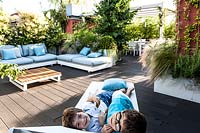 Decked terrace with seating area and children on a lounger looking at camera