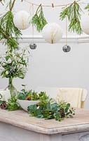 Paper and metal balls hanging from string above table decorated with greenery