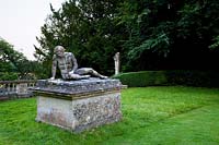 Statue of the dying gladiator on plinth, set on lawn