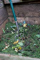 Mixing in grass clippings with vegetable waste on a compost heap. 