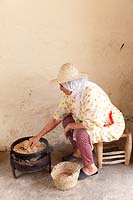 Woman toasting argan nuts to obtain oil