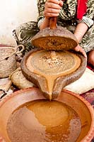 Woman grinding Argan nuts to obtain oil.