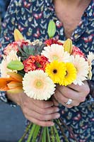 Person holding bouquet of Gerberas and lilies. 