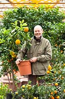 Man holding potted Citrus plant in a nursey