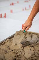 Using a trowel to distribute cement evenly for laying a patio slab