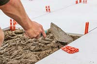 Man using a trowel to distribute cement evenly for laying a patio slab