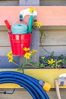 Close up detail of rainbow coloured pallet organiser holding  various garden tools