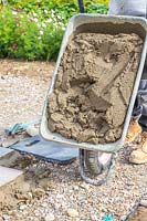 Man tipping barrow filled with cement for laying a patio