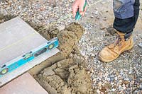 Man adding a trowel of mixed cement to patio base