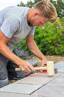 Man using rubber mallet to level paving slap on cement base