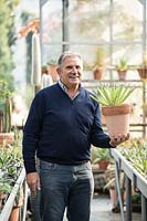 Nurseryman holding a potted Agave in a greenhouse