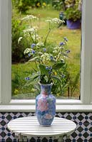 Pentaglottis sempervirens - Green Alkanet - Anthriscus sylvestris - Cow Parsley - in a vase on a table in front of the garden window 