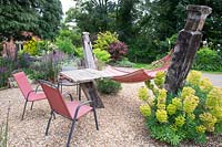 A hammock in a gravel garden with table and chairs