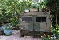 Unusual old military vehicle used as a shed in shaded small town garden