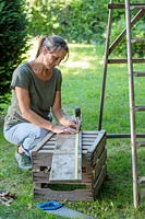 Woman measuring old floor boards to creae shelves for ladder unit