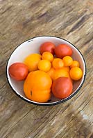 Red and yellow tomatoes in white enamel bowl