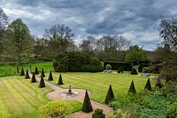 View of formal lawn with pyramids of yew, Taxus baccata and central sundial,