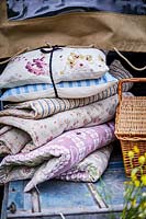 Bundle of vintage floral cushions and blankets at the back of landrover