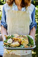 Woman holding roast chicken with herbs