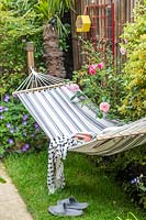 Hammock with cushion and blanket in small tropical garden