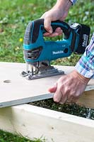 Man using jigsaw in order to create the handle for carrying the coldframe