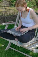 Young girl using a laptop while working and studying from home in the garden. 