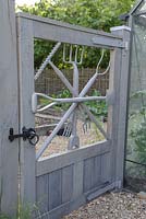 Gate with garden tools by garden designer George Carter, leading to the vegetable garden. 