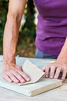 Woman using sandpaper to smooth the surface of the boards. 