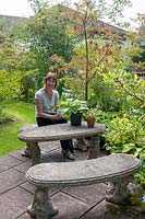 Lorraine Dingwall sitting at the cast concrete bench and table in the back garden. 