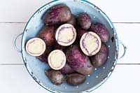 Solanum tuberosum - Washed and cut shetland black potatoes in a colander