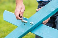 Man using a wrench to tighten nut and washer - assembling picnic bench