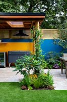 Patio and outdoor room with covered barbecue. Surrounded by a contemporary wooden trellis fence and blue painted wall.