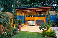 Patio and garden room or pergola at night with garden lighting