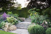 Steps leading up to the Knot Garden from the Croquet Lawn, planted with Stipa tenuissima, Japanese anemones, Lythrum salicaria, sedums and Tetrapanax papyrifer 'Rex'