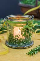 Candle in glass jar with Salvia rosmarinus - Rosemary - sprigs and ribbon