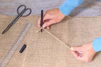 Woman using jute twine and pen to mark a circle on hessian for lining each tier