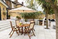 Wooden dining furniture with umbrella with steps up to the house