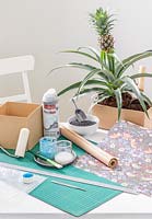 Tools and materials required to make a  cardboard box planted decorated with wrapping paper 