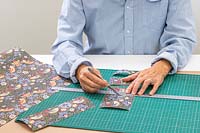 Woman using a craft knife and metal ruler to cut out panels of wrapping paper