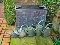 Row of metal watering cans near water trough 